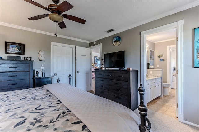 carpeted bedroom featuring ceiling fan, ensuite bath, and ornamental molding