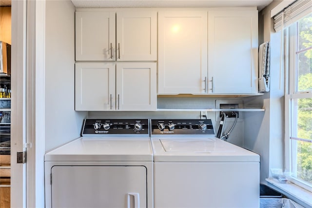 clothes washing area featuring cabinets and washer and dryer