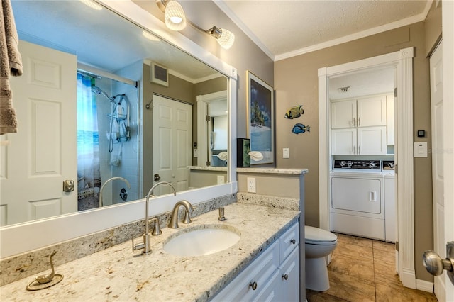 bathroom featuring independent washer and dryer, tiled shower, vanity, ornamental molding, and toilet