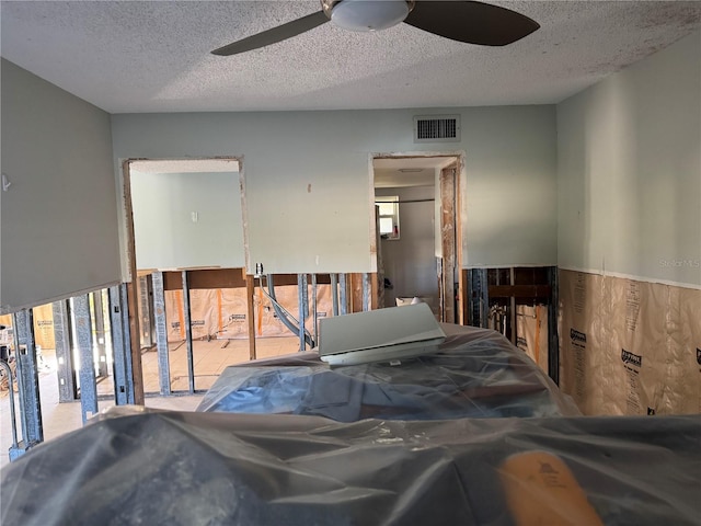 interior space featuring ceiling fan, visible vents, and a textured ceiling