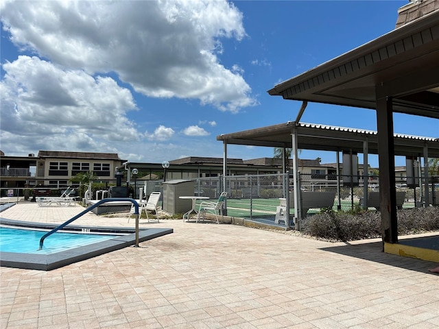 view of patio / terrace with a storage unit, an outdoor structure, fence, and a community pool