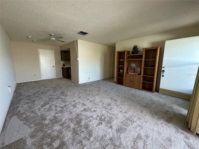 unfurnished living room featuring carpet flooring, a textured ceiling, and ceiling fan