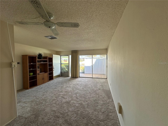 unfurnished room featuring ceiling fan, carpet floors, and a textured ceiling