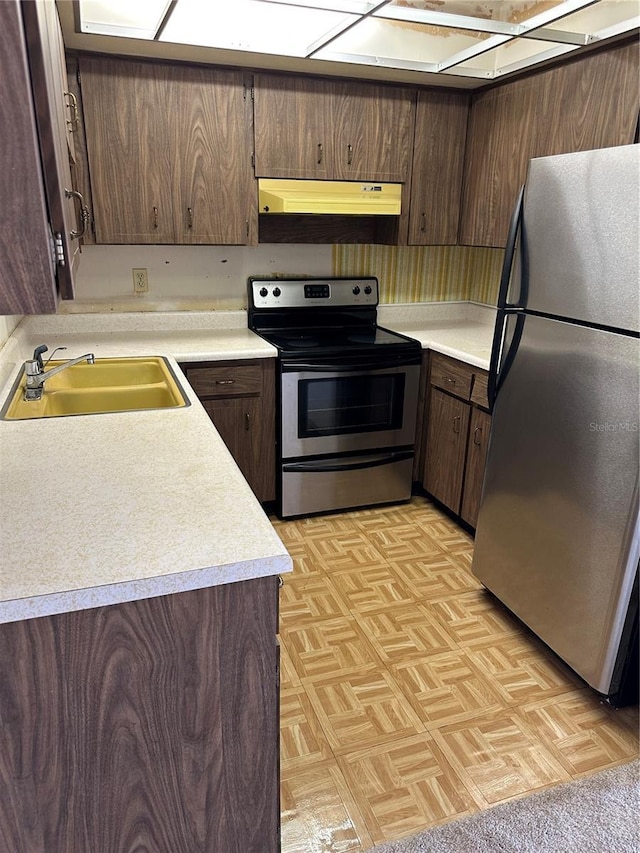 kitchen featuring dark brown cabinetry, appliances with stainless steel finishes, sink, and light parquet floors