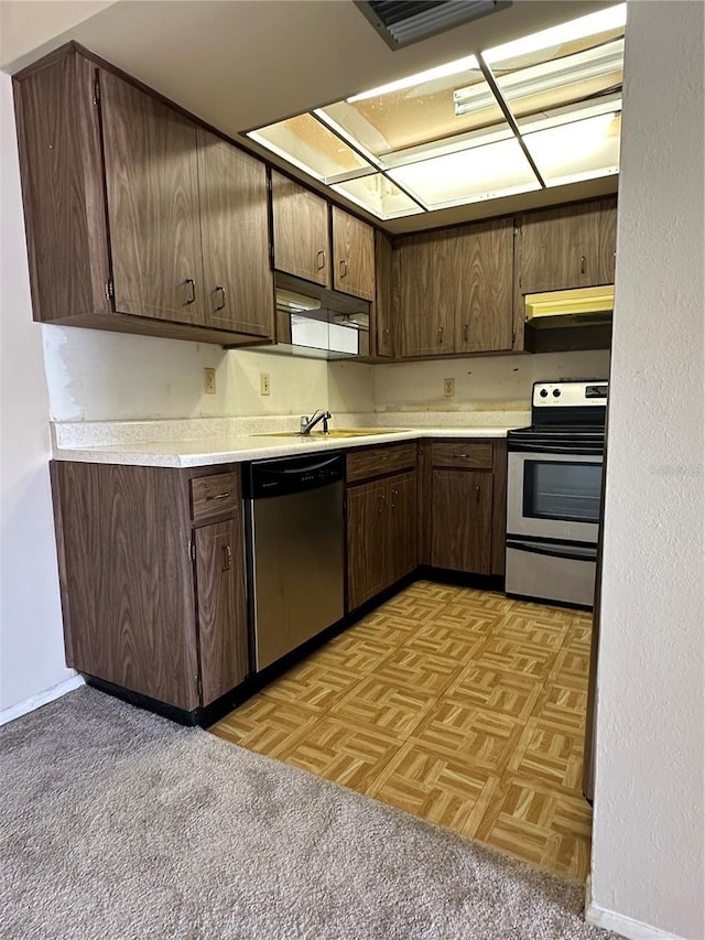 kitchen with light parquet flooring, appliances with stainless steel finishes, sink, and dark brown cabinetry