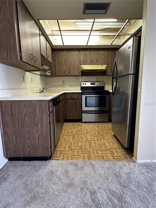 kitchen featuring dark brown cabinetry, stainless steel appliances, light parquet flooring, and sink