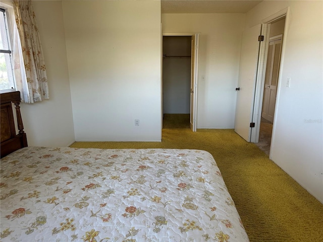 bedroom with a walk in closet and light colored carpet