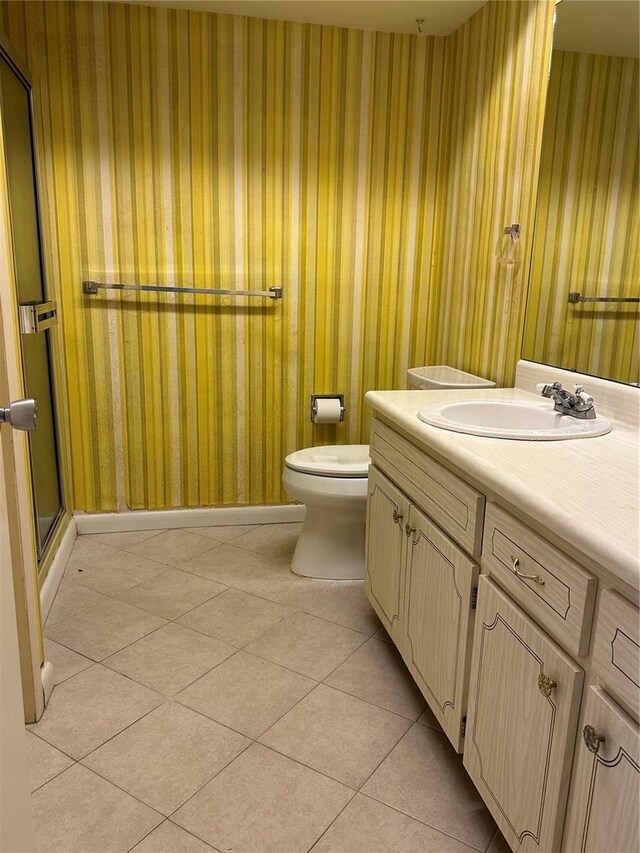 bathroom with vanity, a shower with shower door, tile patterned floors, and toilet