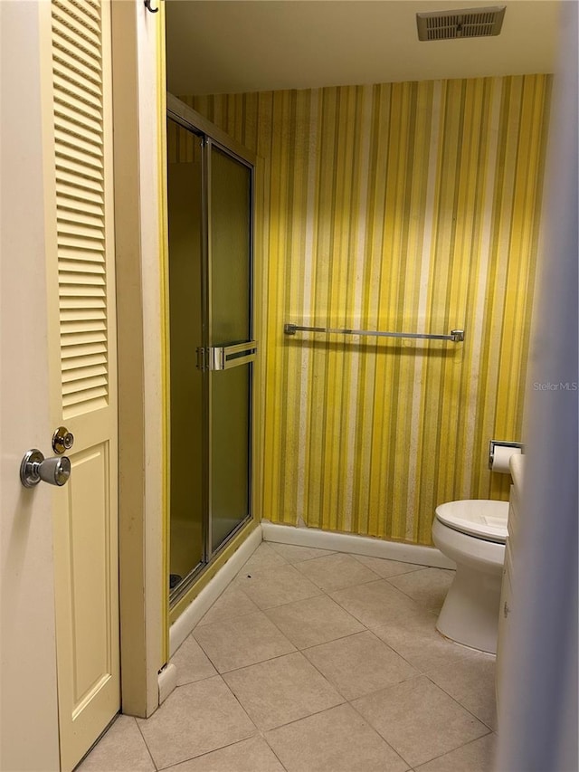 bathroom with an enclosed shower, tile patterned flooring, and toilet