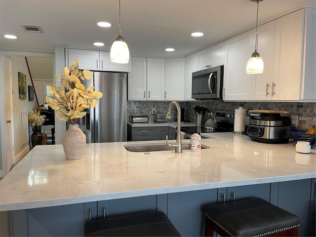 kitchen featuring a breakfast bar, white cabinets, backsplash, hanging light fixtures, and stainless steel appliances