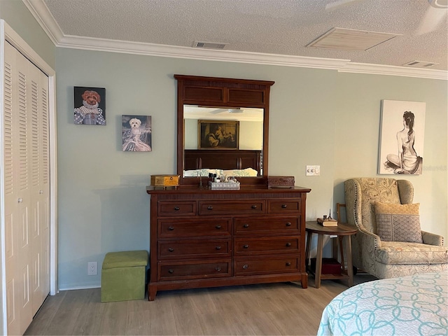 bedroom featuring ornamental molding, a textured ceiling, light hardwood / wood-style floors, and a closet