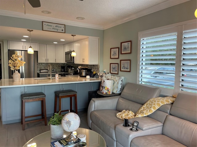 tiled living room featuring sink, ornamental molding, and a textured ceiling