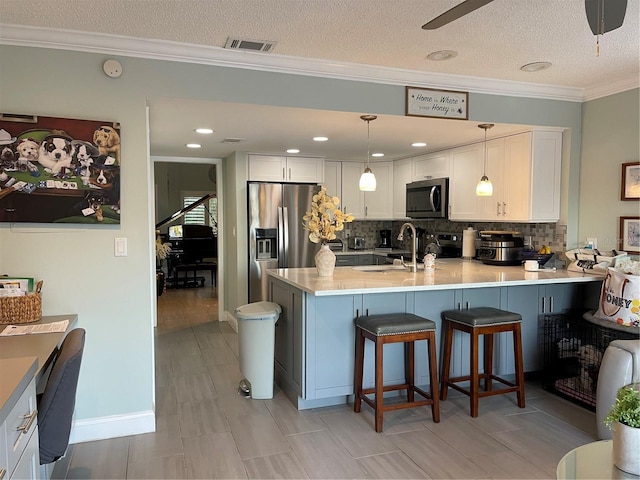 kitchen featuring white cabinetry, decorative light fixtures, appliances with stainless steel finishes, a kitchen breakfast bar, and kitchen peninsula