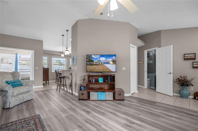 living room with vaulted ceiling, ceiling fan, and light wood-type flooring