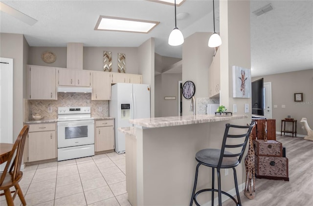 kitchen featuring decorative backsplash, hanging light fixtures, kitchen peninsula, cream cabinets, and white appliances