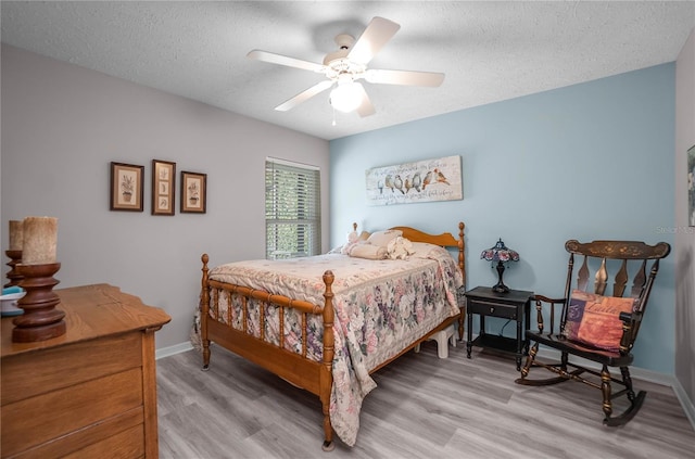 bedroom with ceiling fan, a textured ceiling, and light hardwood / wood-style flooring