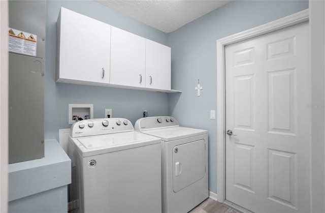 clothes washing area featuring a textured ceiling, cabinets, and washing machine and clothes dryer