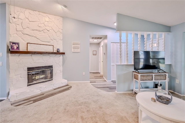 carpeted living room featuring lofted ceiling and a fireplace