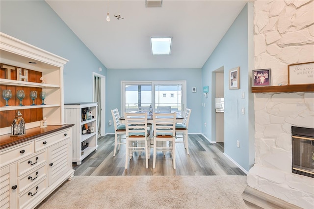 dining room with hardwood / wood-style flooring, lofted ceiling, heating unit, and a fireplace