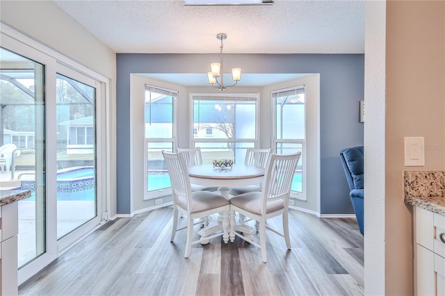 dining room with an inviting chandelier, light hardwood / wood-style flooring, and a textured ceiling