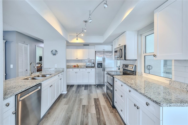 kitchen featuring appliances with stainless steel finishes, a tray ceiling, sink, and white cabinets