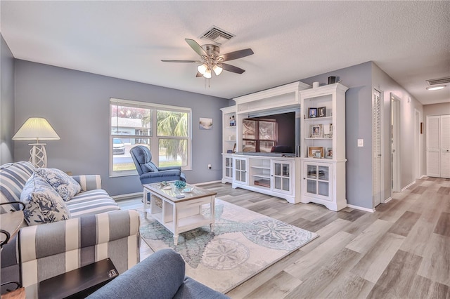 living room with ceiling fan, light hardwood / wood-style flooring, and a textured ceiling