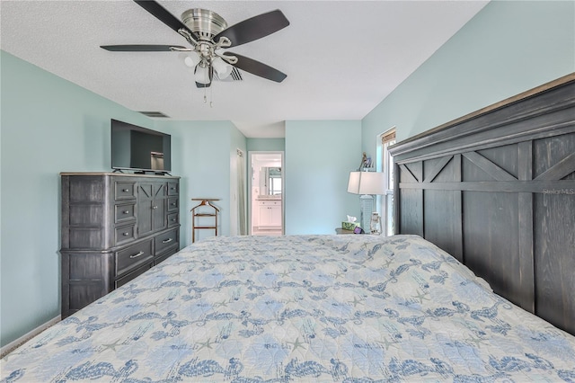 bedroom with ceiling fan, ensuite bath, and a textured ceiling