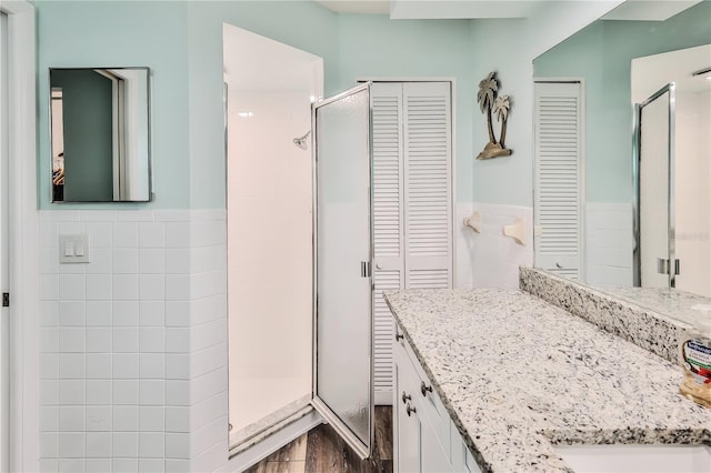 bathroom featuring vanity, a shower with shower door, and tile walls