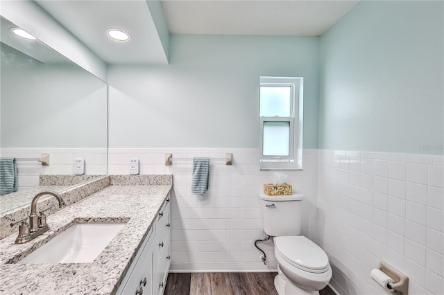 bathroom with hardwood / wood-style flooring, vanity, toilet, and tile walls