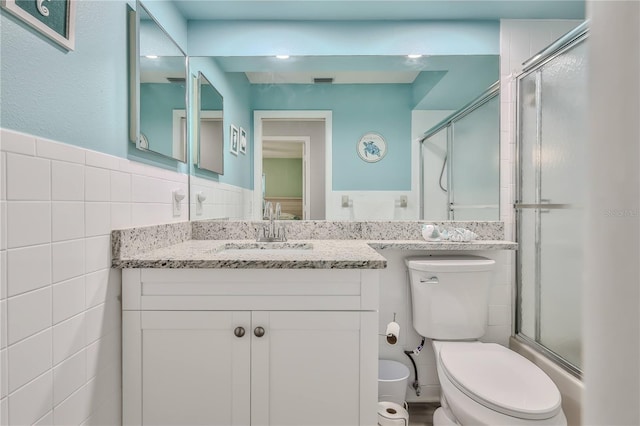 bathroom featuring vanity, a shower with shower door, tile walls, and toilet