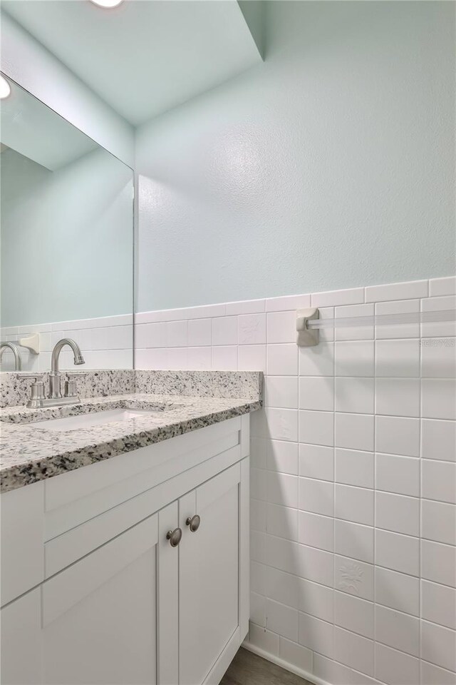 bathroom featuring vanity and tile walls