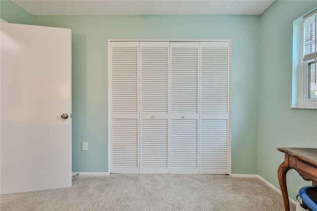 unfurnished bedroom featuring light carpet and a closet