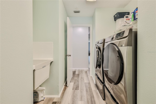 washroom featuring washing machine and clothes dryer and light wood-type flooring