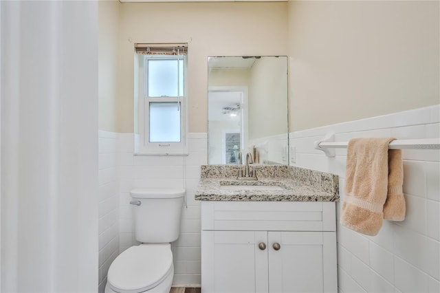 bathroom with vanity, tile walls, and toilet