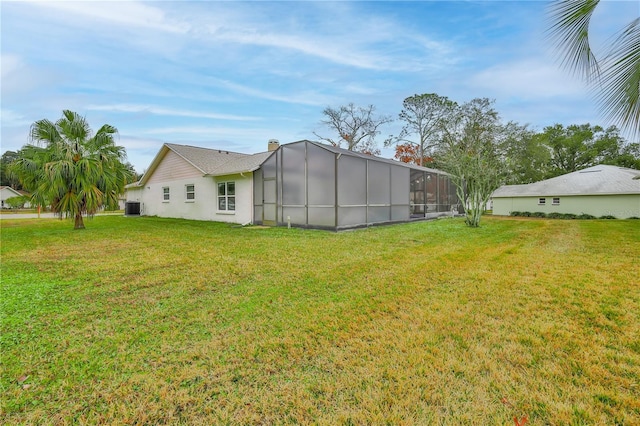 back of property featuring a lanai, a yard, and central air condition unit