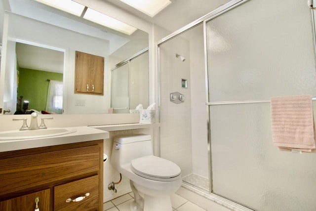 bathroom featuring toilet, vanity, a shower with door, and tile patterned flooring