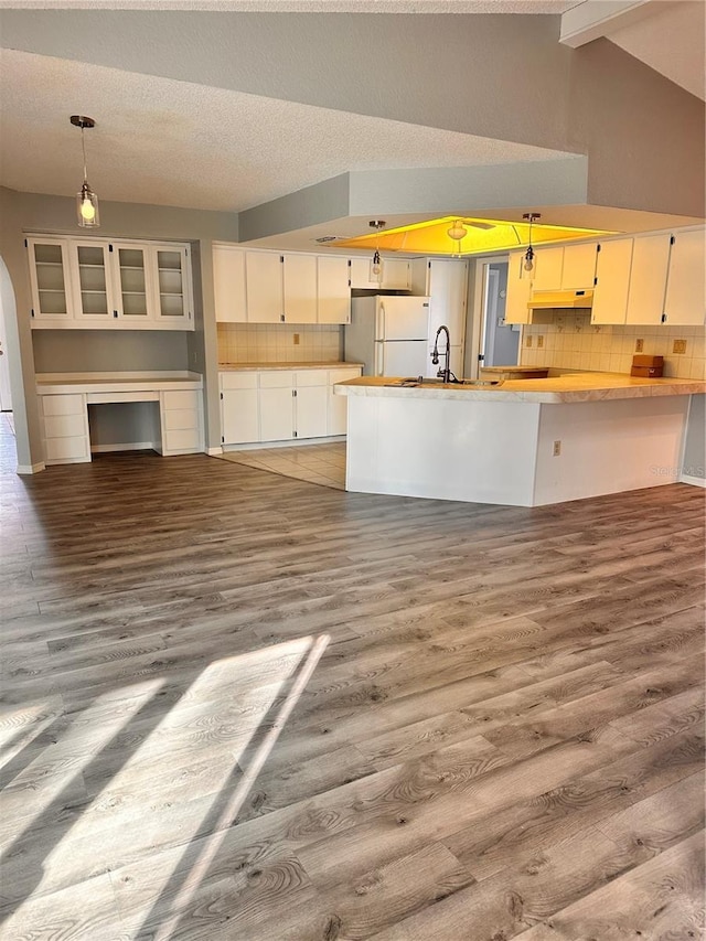 kitchen with white refrigerator, decorative light fixtures, hardwood / wood-style floors, and backsplash