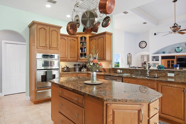 kitchen with light tile patterned flooring, sink, dark stone counters, a center island, and stainless steel appliances