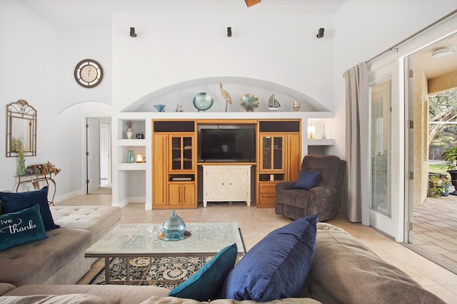 tiled living room featuring a towering ceiling and built in features