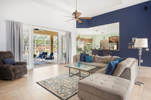 living room featuring light tile patterned flooring, ceiling fan, a raised ceiling, and a towering ceiling