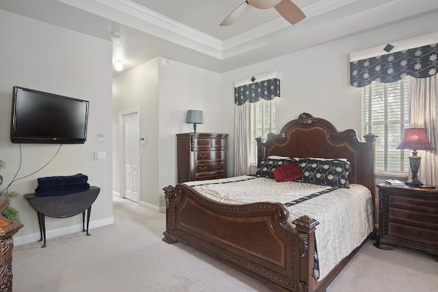 bedroom with ornamental molding, light colored carpet, ceiling fan, and a tray ceiling