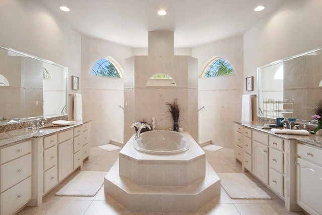 bathroom featuring tiled tub, vanity, plenty of natural light, and tile walls