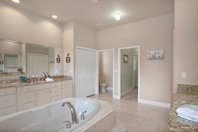 bathroom with tile patterned flooring, vanity, a relaxing tiled tub, and toilet