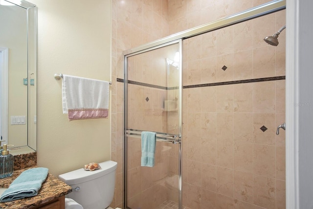 bathroom with a shower with door, vanity, and toilet