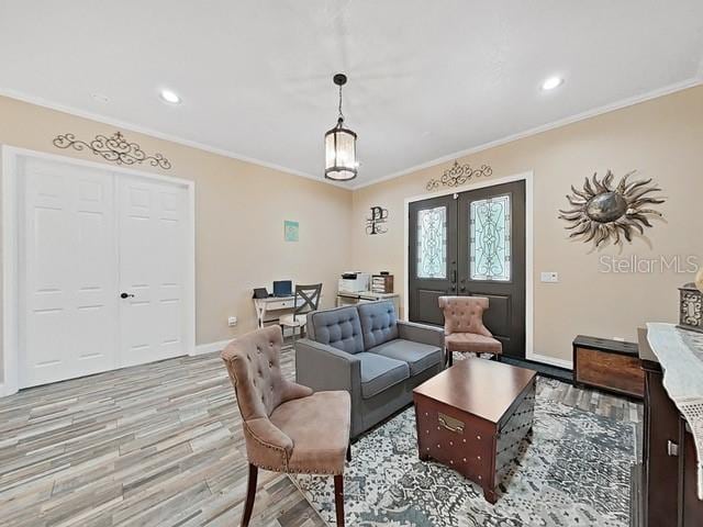 living room featuring french doors, crown molding, and light wood-type flooring