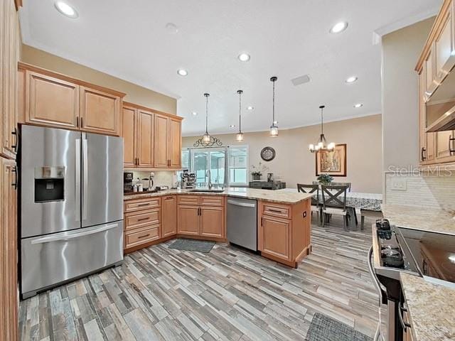 kitchen featuring sink, light hardwood / wood-style flooring, stainless steel appliances, decorative light fixtures, and kitchen peninsula