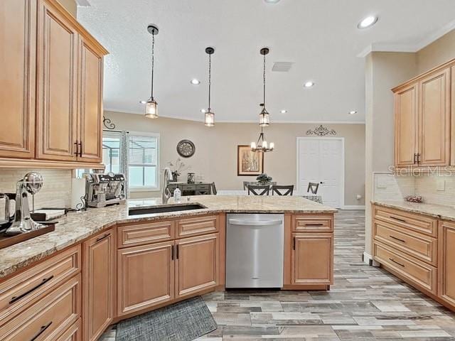 kitchen featuring light stone counters, sink, decorative light fixtures, and stainless steel dishwasher