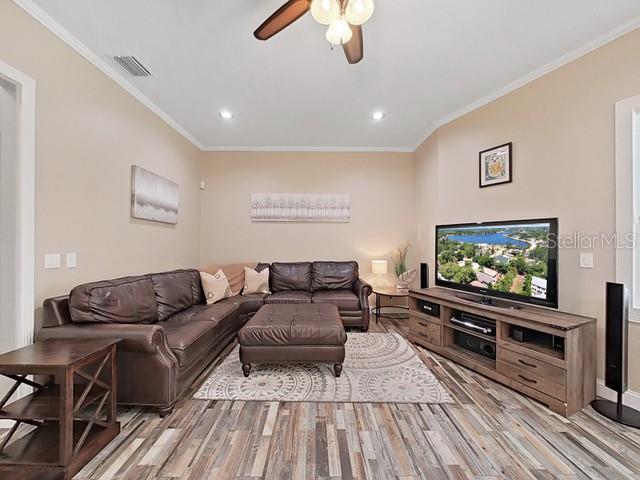 living room featuring ornamental molding, ceiling fan, and light hardwood / wood-style floors