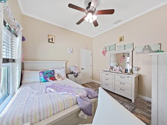 bedroom with hardwood / wood-style flooring, ceiling fan, and ornamental molding