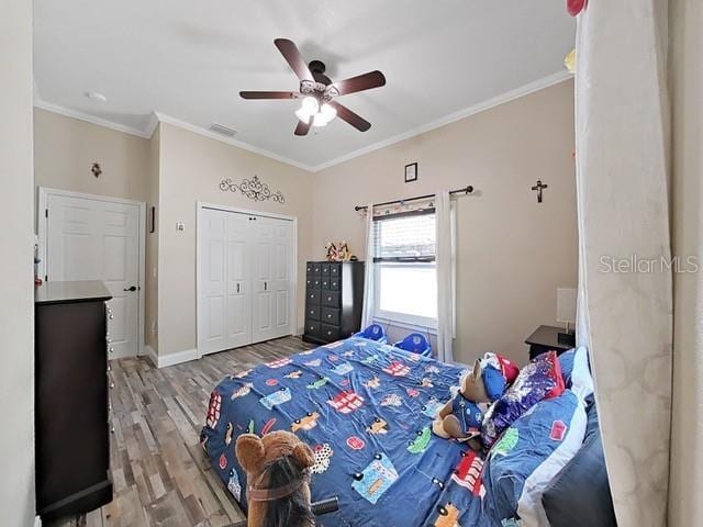 bedroom featuring hardwood / wood-style flooring, ornamental molding, ceiling fan, and a closet